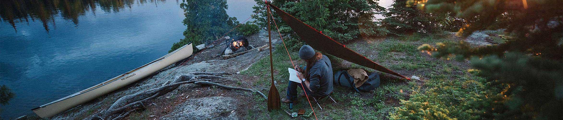 A camper exploring the backcountry wilderness with a canoe