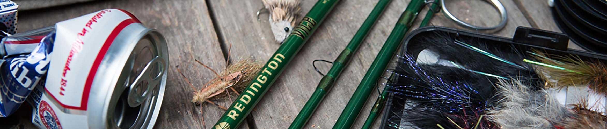 A Redington fly rod rests between a fly box and popular fly patterns.