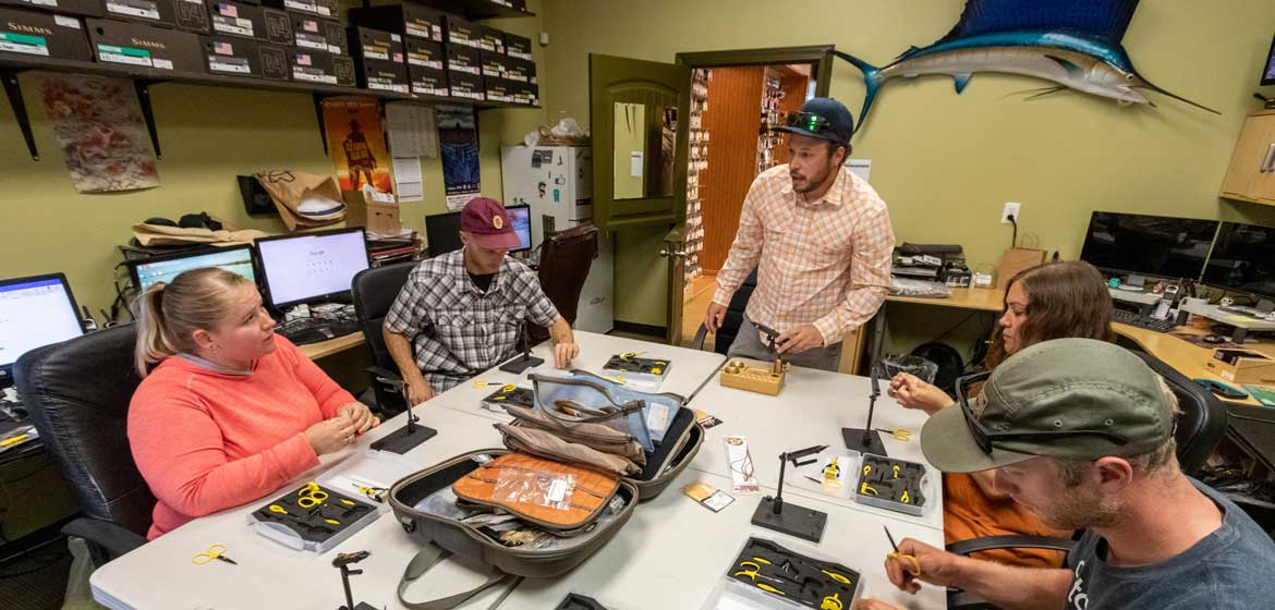 An instructor helping a student tie a fly in an intermediate fly tying class at Fishwest in Sandy, UT