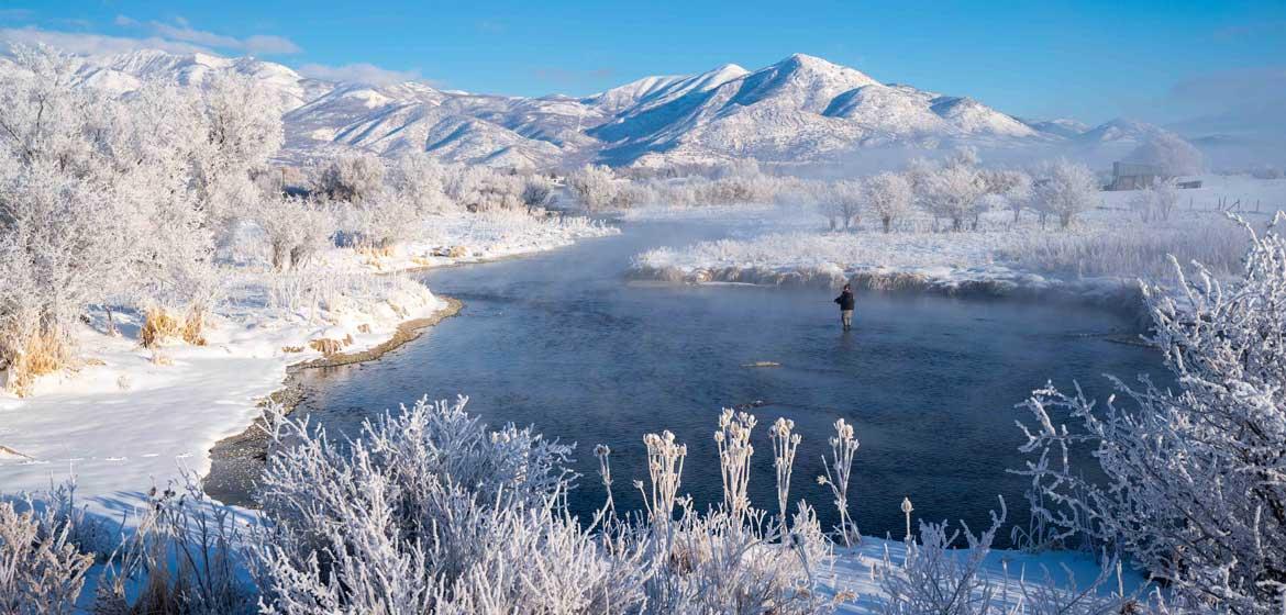 A fisherman casts on a river surrounded by snow in Northern Utah.