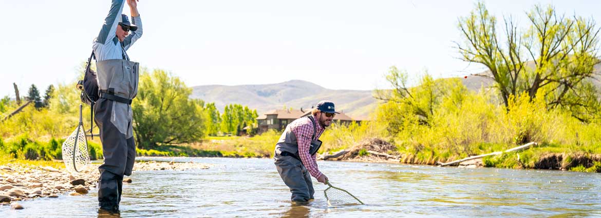 A fly fishing guide instructs a client on a river in Northern Utah