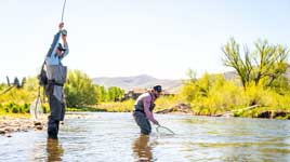 A fly fishing guide instructs a client on a river in Northern Utah