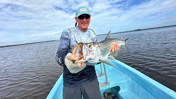 An angler holds a beautiful juvenile tarpon caught while fishing at the Tarpon Cay Lodge.