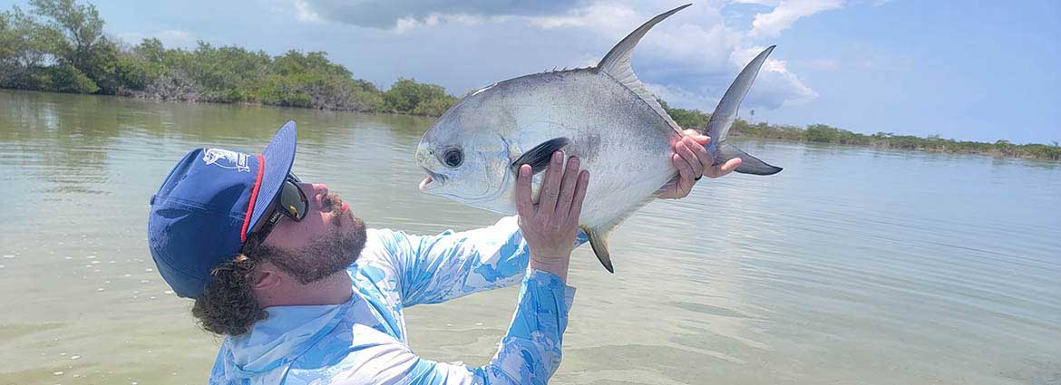 An angler admires a permit (palometa) caught on the flats of Chetumal Bay with Fishwest.