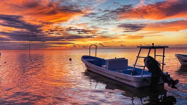 A beautiful sunrise crests the horizon as a boat is prepared for a day of fishing on the flats of Xcalak, Mexico.